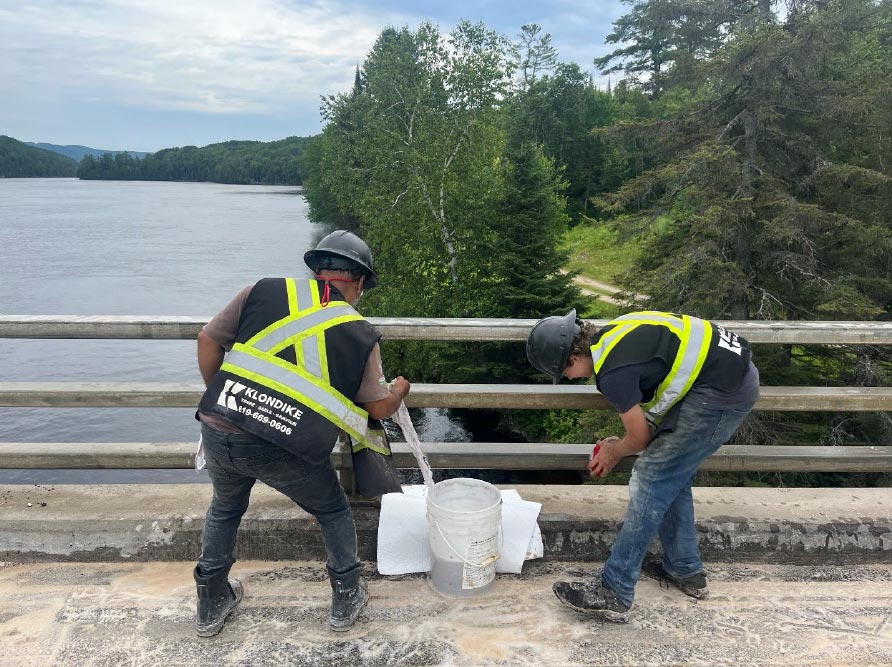 Photo qui représente deux travailleur qui nettoient des garde-fous